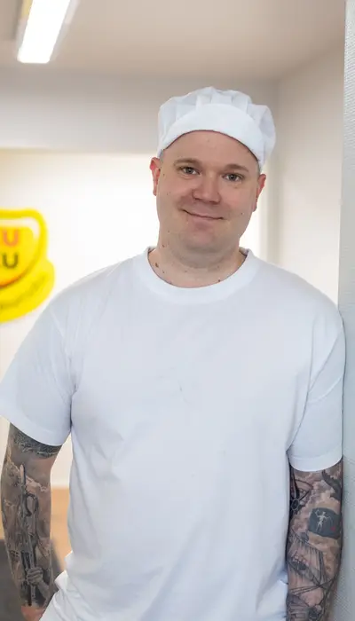 Valkoiseen t-paitaan ja hattuun pukeutunut mies.